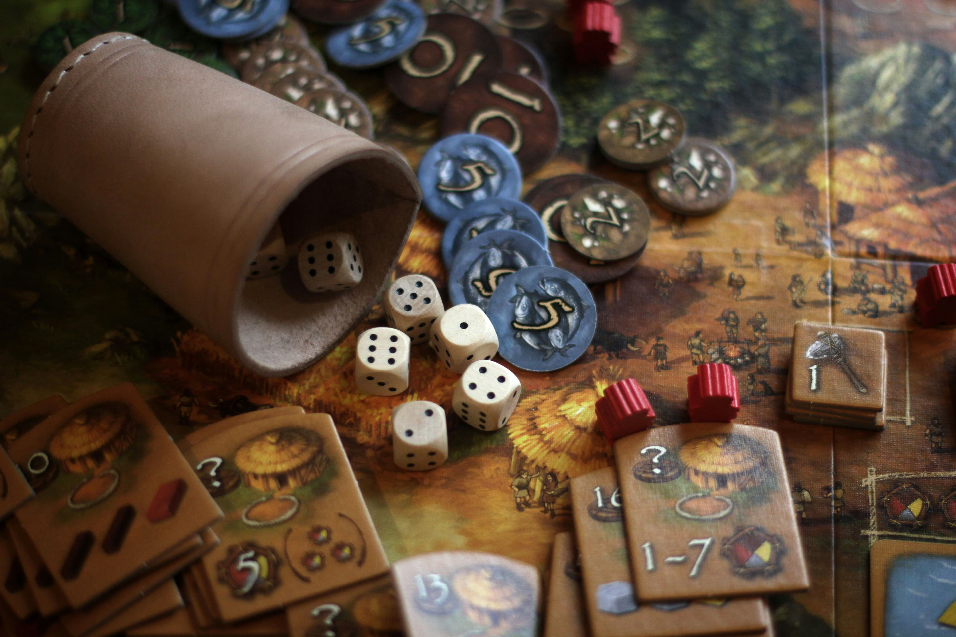 Dados, fichas e peças de jogo espalhados sobre a mesa